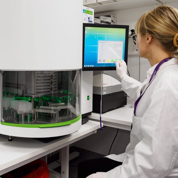 Nainen näppäilee DNA-eristyslaitetta laboratoriossa.